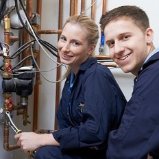 EIn Anlagenmechaniker und eine Anlagenmechanikerin vor einer Kupferleitung